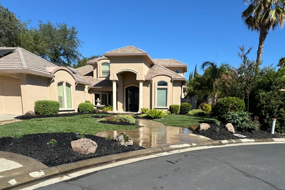 Beautiful front yard with green grass and plants and islands of mulch and rocks